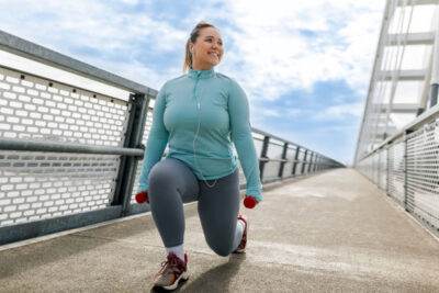 overweight woman exercising with dumbbells on bridge